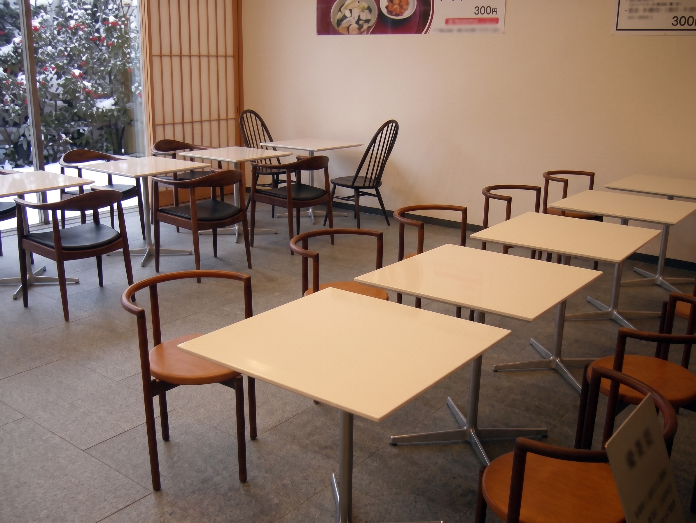 木製テーブルと椅子が並ぶ飲食店の客席スペース